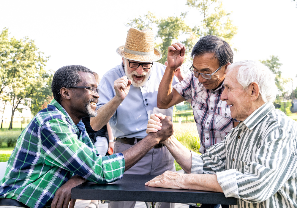 a group of senior men arm wrestling and cheering at the park