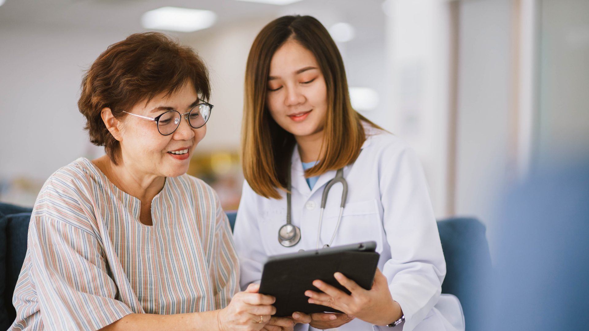 asian doctor with a patient on a tablet