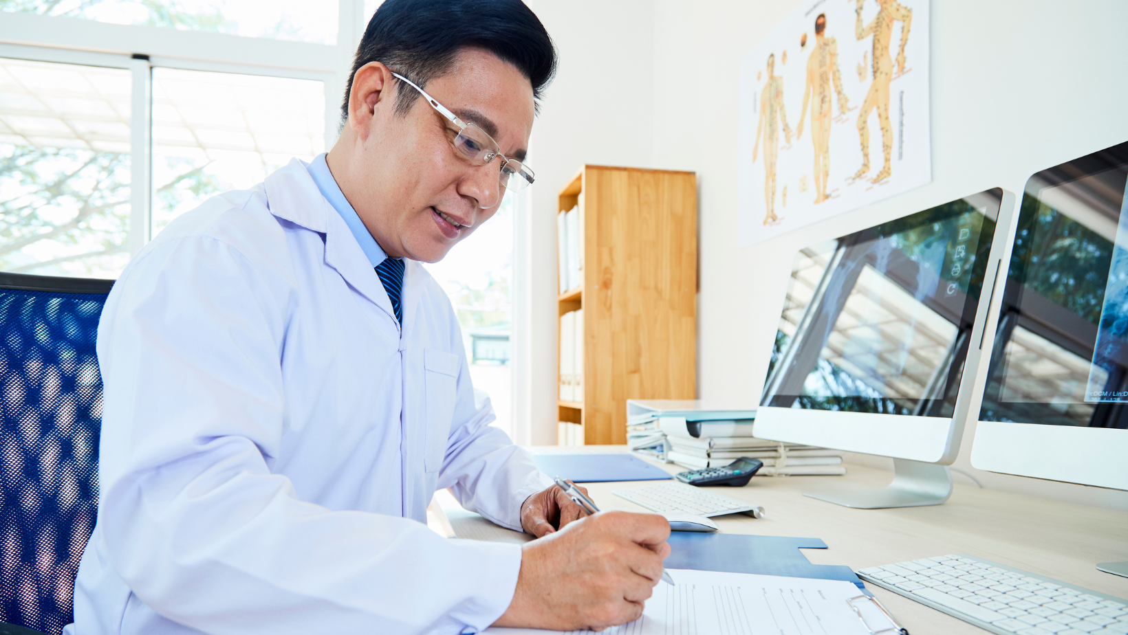 asian male doctor writing notes