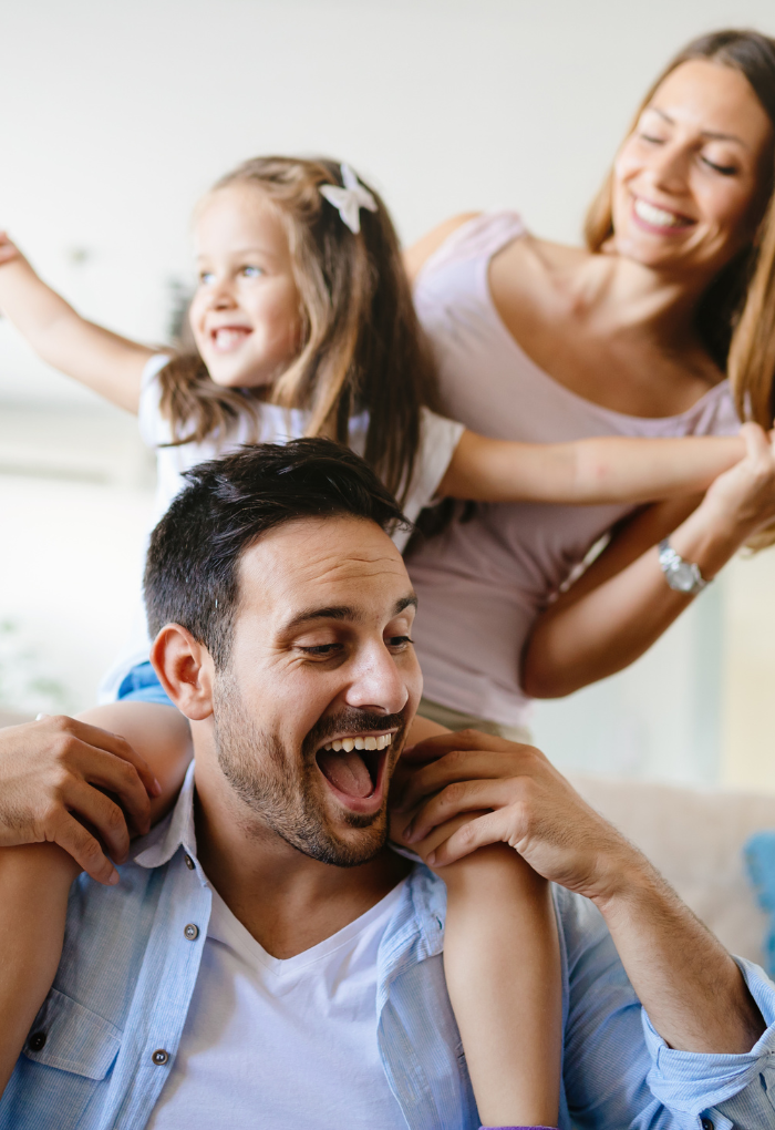 young father with daughter on shoulders and wife