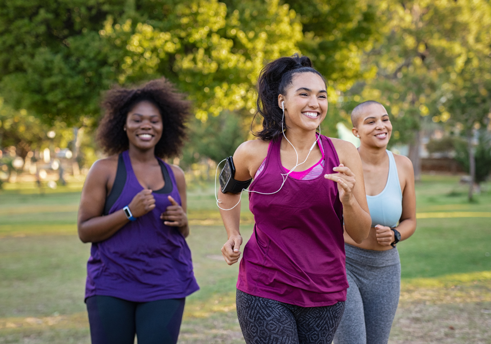 three women running and smiling through a park