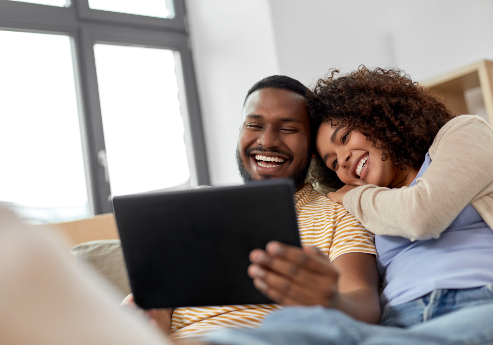 black couple smiling at tablet